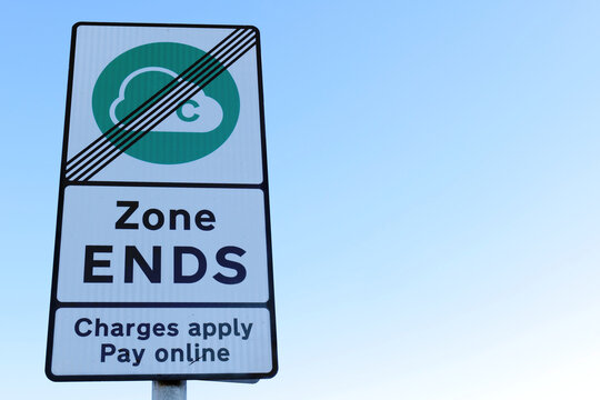 A close up of a reflective Clean Air Zone roadside sign, showing the end of the payment zone. Copy space available in the sky to the right.