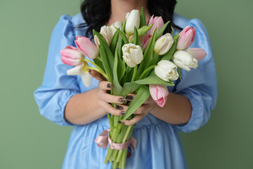 Mature woman with bouquet of beautiful tulips on green background. International Women's Day