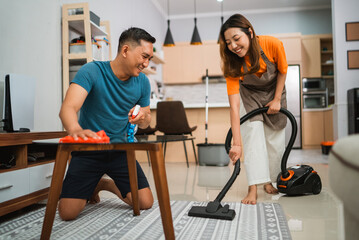 joyful couple doing household chores together in the living room
