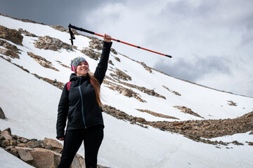 Mujer excursionista alzando su bastón en señal de triunfo por subir hasta la Laguna de Los Tres,...