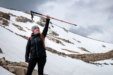 Papier Peint photo autocollant Fitz Roy Mujer excursionista alzando su bastón en señal de triunfo por subir hasta la Laguna de Los Tres, en el Chalten, Patagonia