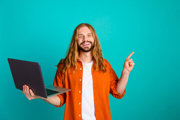 Portrait of handsome optimistic man with long hairstyle hold laptop indicating at sale empty space...