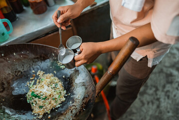 hand of male seller seasoning fried rice on the wok