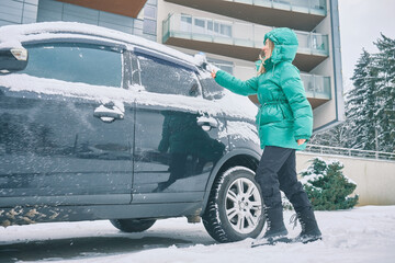 Woman remove her car from snow, Clean car window in winter from snow emoving snow from car...
