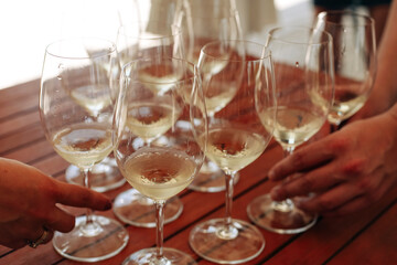 Glasses with different types of wine and human hands holding wine glasses in the background