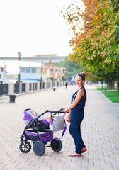 Outdoor portrait of a happy mother and son. Baby sitting in stroller