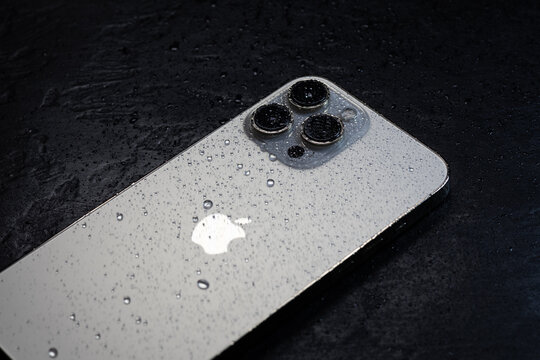 KYIV, UKRAINE - October 20, 2023 : Modern smartphone Apple iPhone 15 Pro with water drops on black background. Water resistant modern technology.