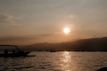 Fototapeta na wymiar Fishing boats sail towards the island. Early morning and sunrise over the mountains