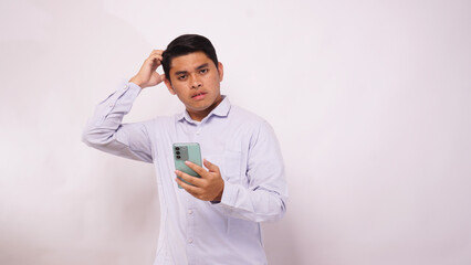 Asian man scratch his head while holding mobile phone and showing confused face expression
