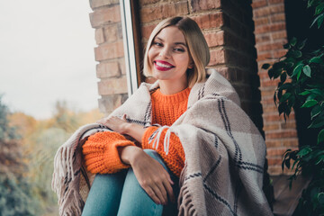 Photo of adorable carefree girl toothy smile sit window sill covered warm blanket enjoy free time...