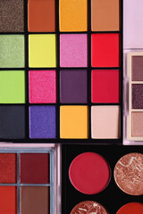 Various colorful eyeshadow palettes on bright pink background. Flat lay.
