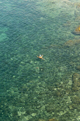 older Woman swimming in a turquoise sea. view from above