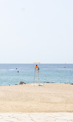 a lifeguard on the tower on the beach. watches over vacationers at sea. Mediterranean. Spain. vertical