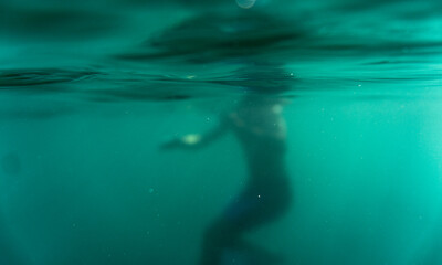 blurred Man underwater. A person submerged in clear blue water with bubbles. Surreal scene. creative