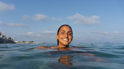 closeup of brunette latin girl smiling at the camera in the sea