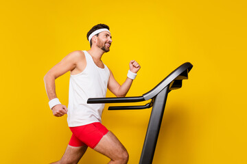 Profile portrait of determined fitness man running treadmill empty space ad isolated on yellow...
