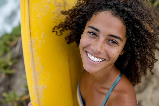 Biracial woman smiling holding surfboard, energetic and bold. - Powered by Adobe