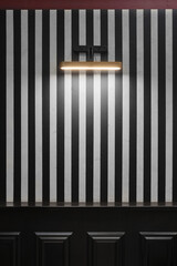 Illuminated black and white wall by wall modern lamp.Wooden black cornice moulding . background with copy space