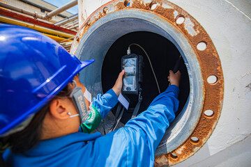 Worker female hand holding gas detector inspection safety gas testing at front manhole tank chemical to work inside confined space - obrazy, fototapety, plakaty