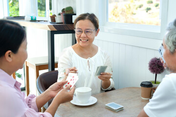 active asian senior pensioners enjoy free time with playing cards game together, concept elderly...