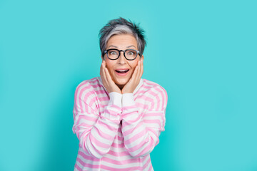 Photo of impressed funky lady wear striped sweater spectacles arms hands cheeks empty space isolated turquoise color background