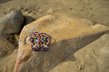 Flip-flops on the rocks at the beach, summer, beach, and sun concept.