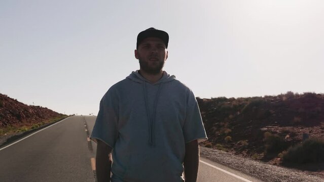 Camera zooms in on young excited man on highway watching epic cinematic sunny sandstone desert Arizona with mouth open.