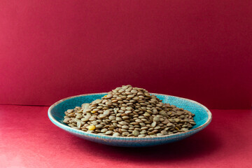 Lentils in a blue plate on a red background. Close-up with lovely details.