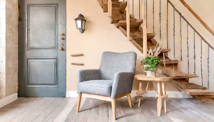 Grey armchair and wooden rustic bench near door against beige wall and staircase. French country, farmhouse interior design of modern entryway.