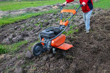 agricultural landscape transforms under the influence of a dedicated farmer and a robust motor cultivator, priming the soil for cultivation. © Maryna