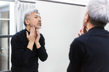 鏡を見ながら顎を触る男性/メンズビューティー