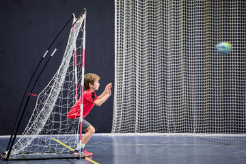 Détermination juvénile, enfant de huit ans gardien débutant arrêtant le ballon au handball