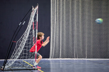 Détermination juvénile, enfant de huit ans gardien débutant arrêtant le ballon au handball