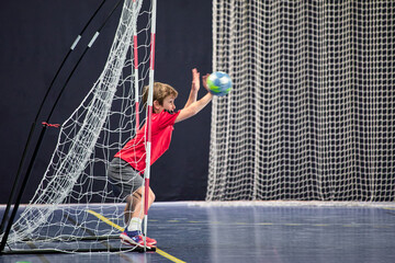 Détermination juvénile, enfant de huit ans gardien débutant arrêtant le ballon au handball