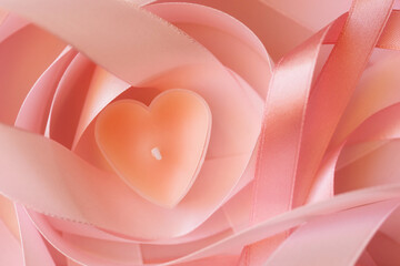 candle tablet in shape of heart on background of pink ribbons. valentine's day.