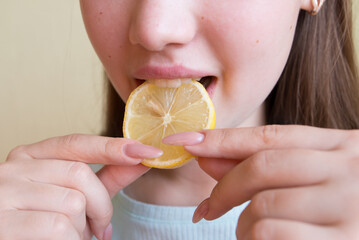 young beautiful girl eating lemon, close-up, crop photo. mouth eating a slice of lemon