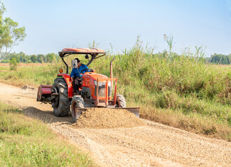 Obraz premium A stone-plowing tractor is leveling the road surface.