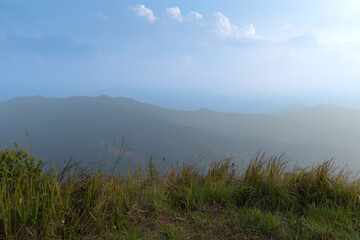 The foreground is covered with grass. Landscape view of mountain ranges lined up background. Under fog covers the sky. At Phu Langka Phayao Province of Thailand. 