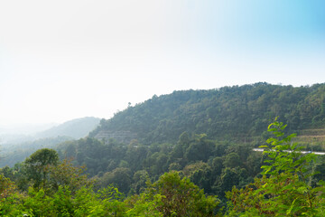 Landscape view of mountain at Khao Plung Rest Stop Uttaradit Thailand. Road cuts through the mountains. Under light of blue sky.