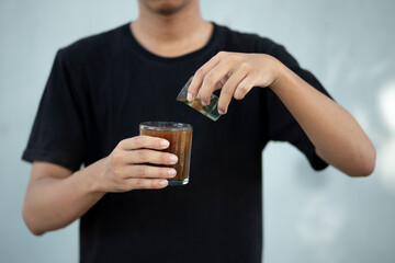 Front view close up of a man hands holding a coffee cup and liquid sugar at home