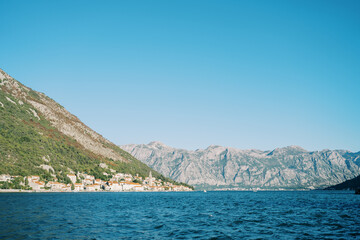Fototapeta na wymiar View from the sea of the coast of Perast at the foot of the mountains surrounded by a mountain range. Montenegro