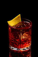 Classic Negroni Cocktail in a retro glass with ice and orange peel on a black background.