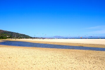 view from the Playa Valdevaqueros beach over the Atlantic with many windsurfers with the city of...