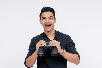 Excited young Filipino male smiling widely with binoculars, isolated on a white background,...