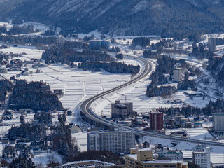 Snow-Clad Cityscape and Highway
Elevated view of a curving highway winding through a city blanketed...