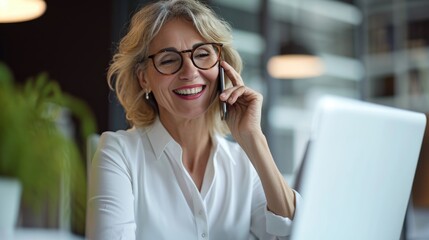 Happy smiling mature middle aged business woman, 40s professional lady executive manager talking on the cell phone making business call on cellphone at work in office