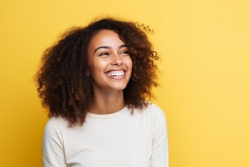 Portrait of a beautiful young african american woman smiling over yellow background