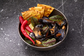 Mussels in a plate, with chilli pepper shot from the top with lemon and toasted bread.Copy space.Selective focus