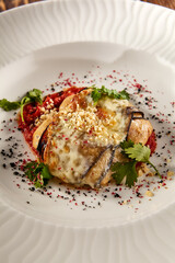 Baked eggplant roll with cheese and tomatoes, elegantly plated on a white dish