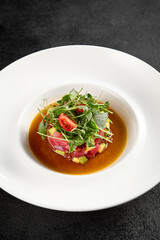 Tuna and avocado tartare topped with microgreens and cherry tomatoes, served in a white bowl
